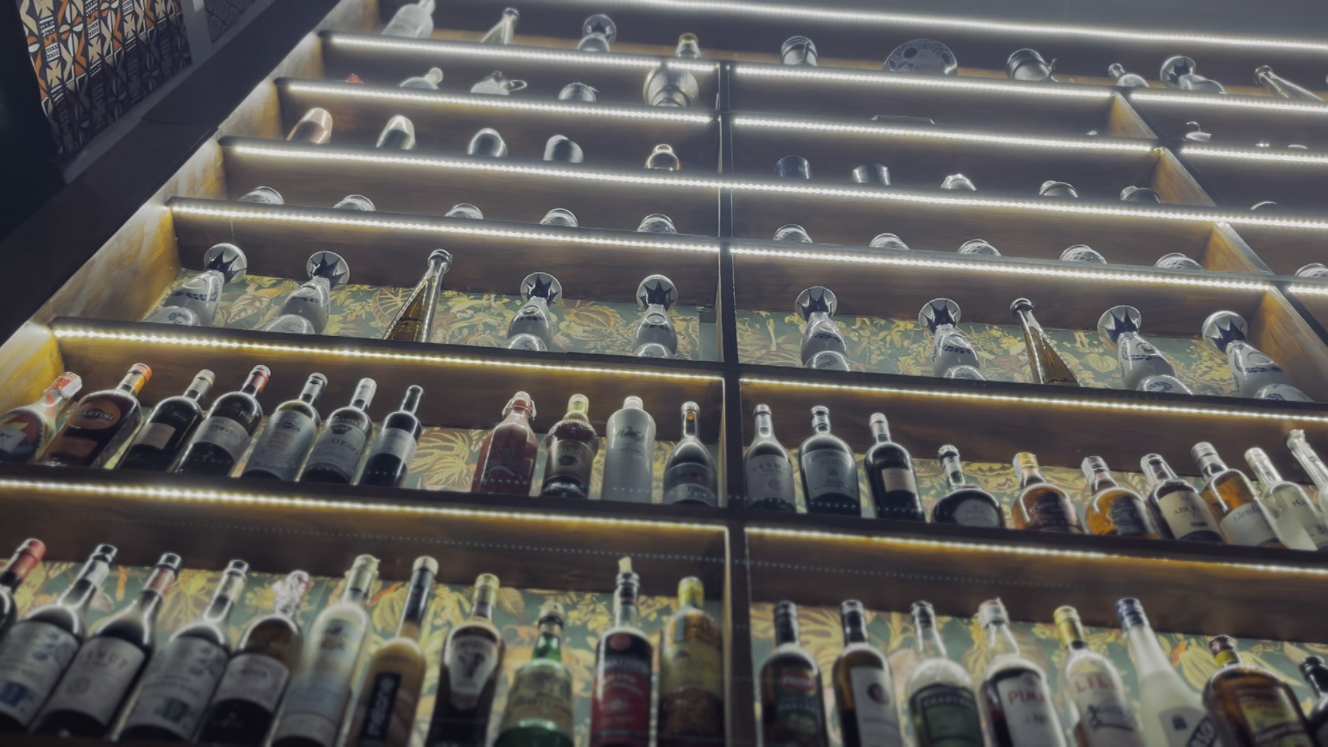 El backbar iluminado de Solo Cocktail School con su colección de destilados