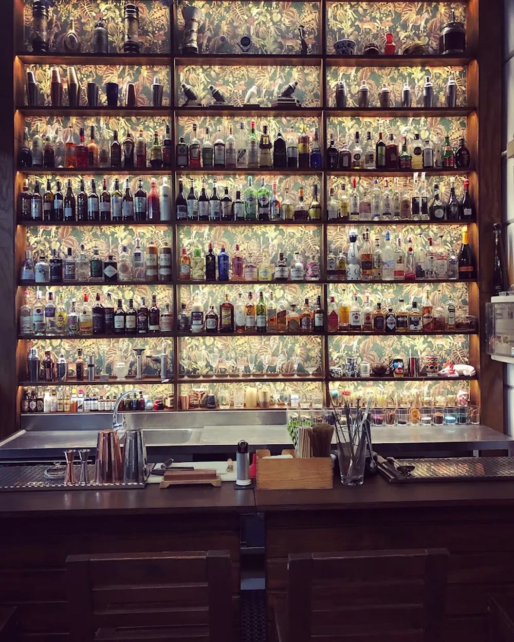 La pared de botellas iluminada con su papel botánico